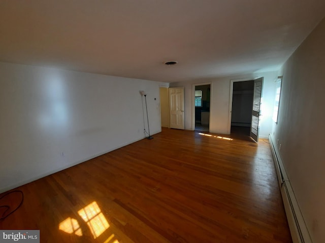 unfurnished room featuring wood-type flooring and a baseboard heating unit