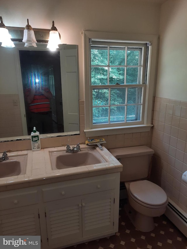 bathroom featuring toilet, vanity, tile walls, and a baseboard heating unit