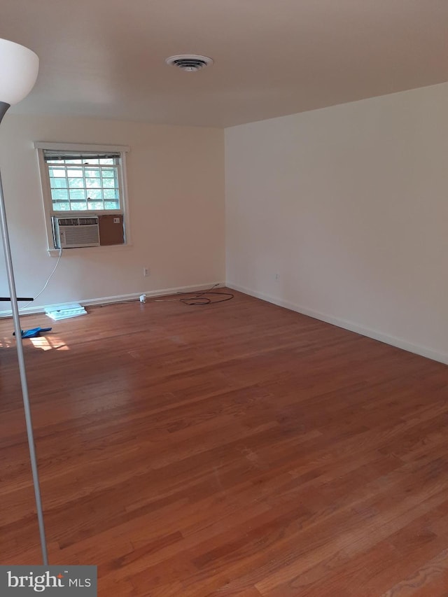 empty room with hardwood / wood-style flooring, a baseboard radiator, and cooling unit