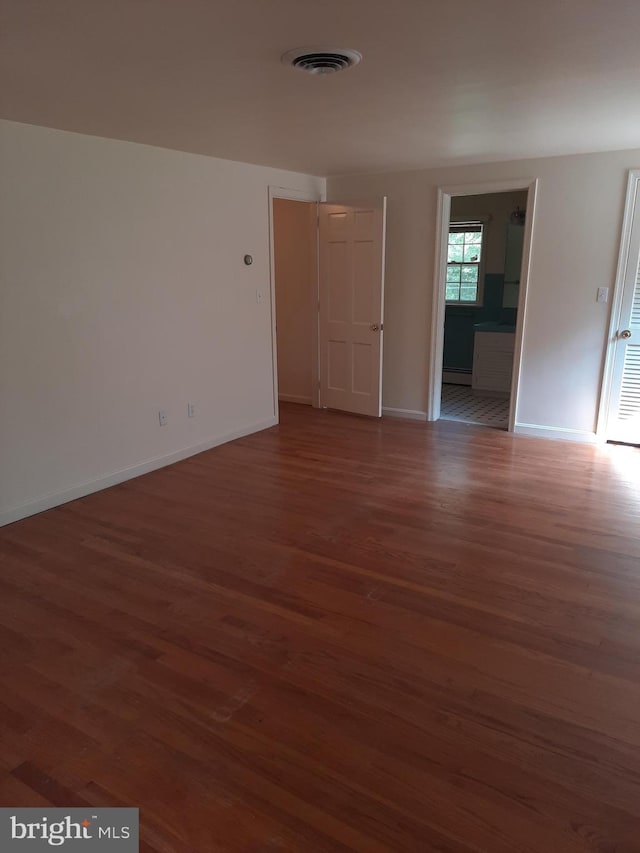 spare room with dark hardwood / wood-style floors and baseboard heating