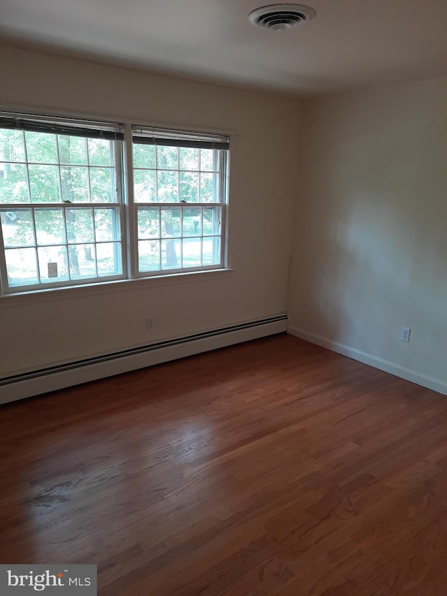 empty room featuring baseboard heating and dark hardwood / wood-style flooring