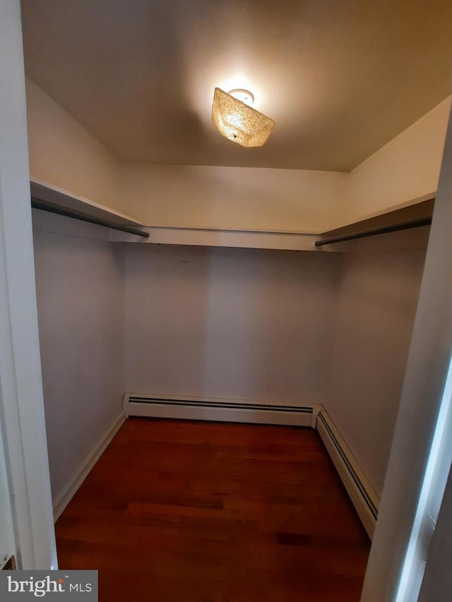 walk in closet with dark hardwood / wood-style flooring and a baseboard heating unit