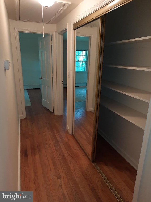 corridor with baseboard heating and dark hardwood / wood-style flooring