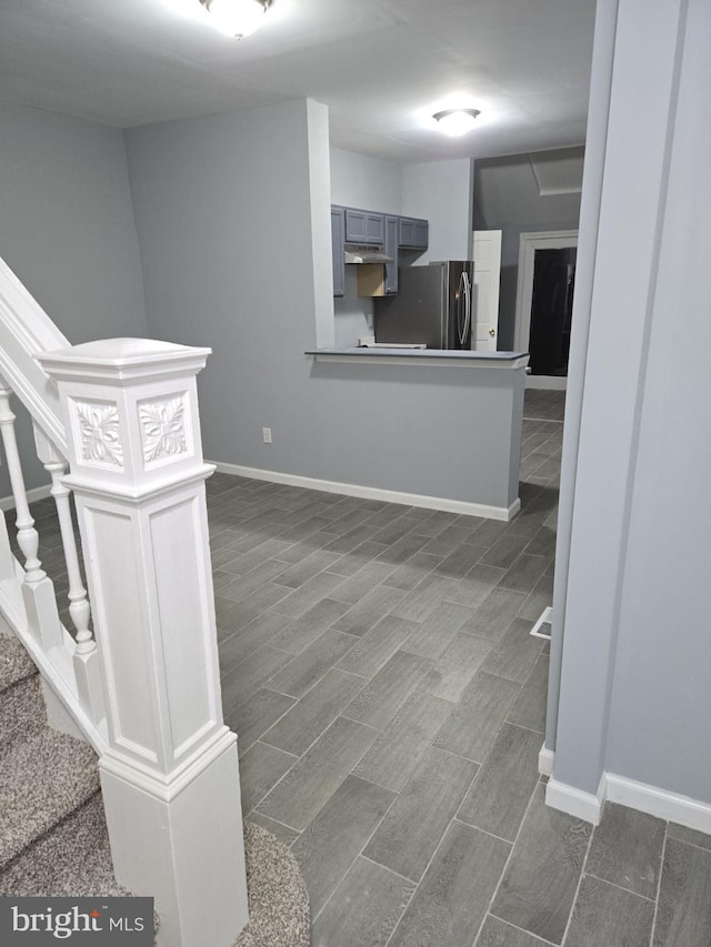 kitchen featuring gray cabinets, dark hardwood / wood-style flooring, kitchen peninsula, and stainless steel refrigerator