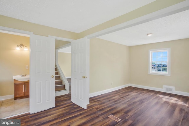 unfurnished room featuring a textured ceiling, sink, and dark hardwood / wood-style floors