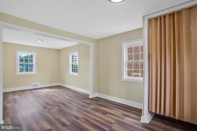 unfurnished room with dark hardwood / wood-style flooring