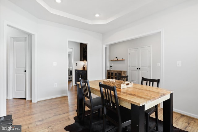 dining area featuring light hardwood / wood-style floors and a raised ceiling