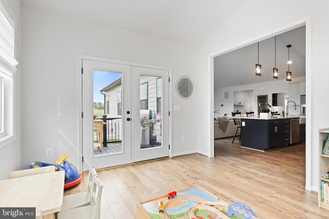 rec room featuring french doors, light wood-type flooring, lofted ceiling, and sink