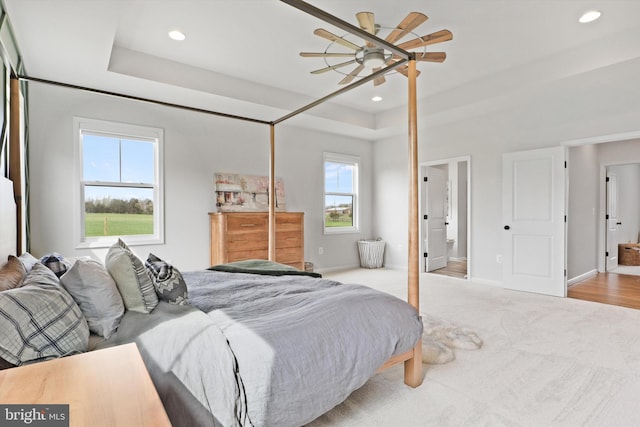 bedroom featuring ceiling fan, ensuite bath, light wood-type flooring, and multiple windows