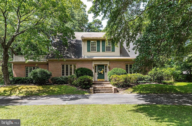 view of front of house featuring a front yard, aphalt driveway, and brick siding