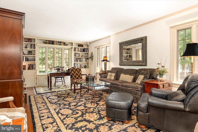 living room featuring built in shelves, ornamental molding, and wood-type flooring