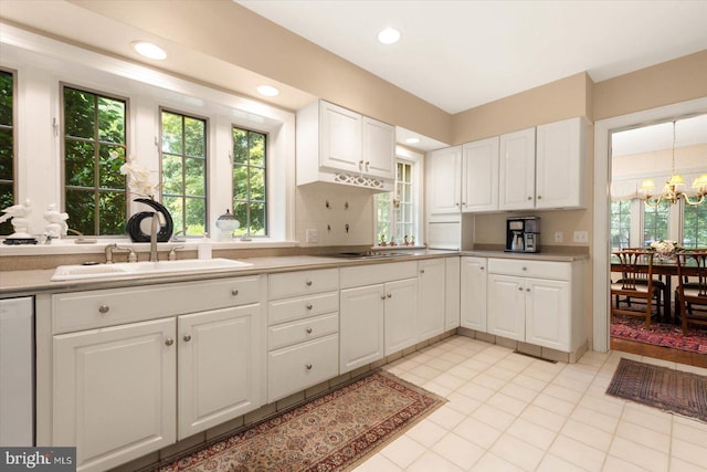 kitchen with backsplash, gas stovetop, dishwashing machine, sink, and white cabinets