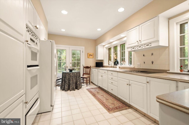 kitchen featuring sink, backsplash, white appliances, and white cabinets