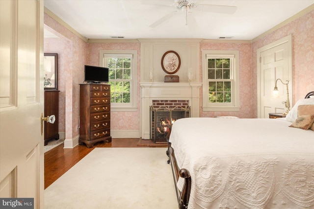 bedroom with a fireplace, hardwood / wood-style floors, and ceiling fan