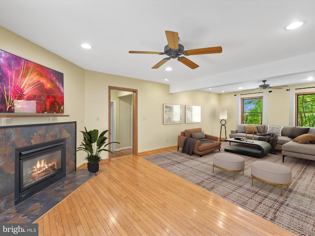 living room with a tile fireplace, hardwood / wood-style flooring, and ceiling fan