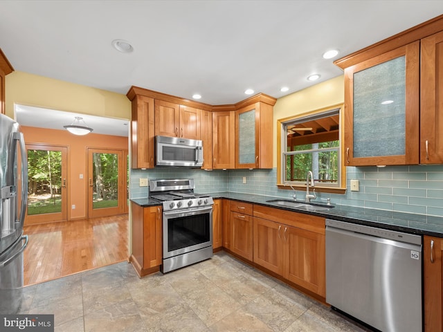 kitchen featuring a healthy amount of sunlight, sink, stainless steel appliances, and dark stone counters