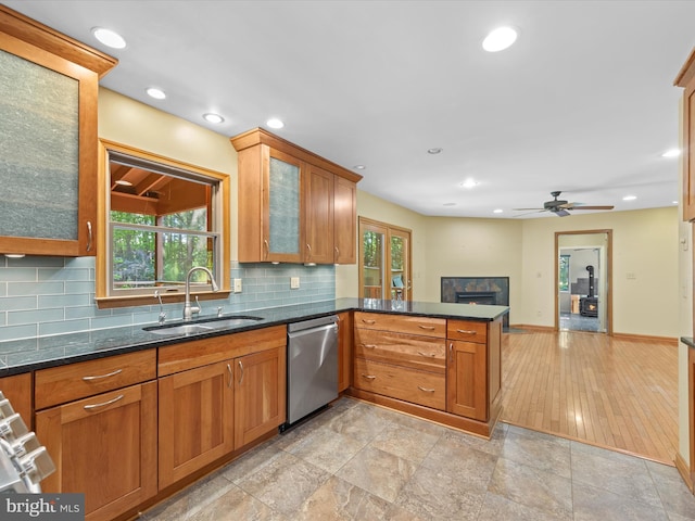 kitchen featuring dishwasher, sink, dark stone countertops, light hardwood / wood-style floors, and kitchen peninsula