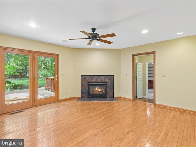 unfurnished living room featuring ceiling fan, a tile fireplace, and light hardwood / wood-style flooring