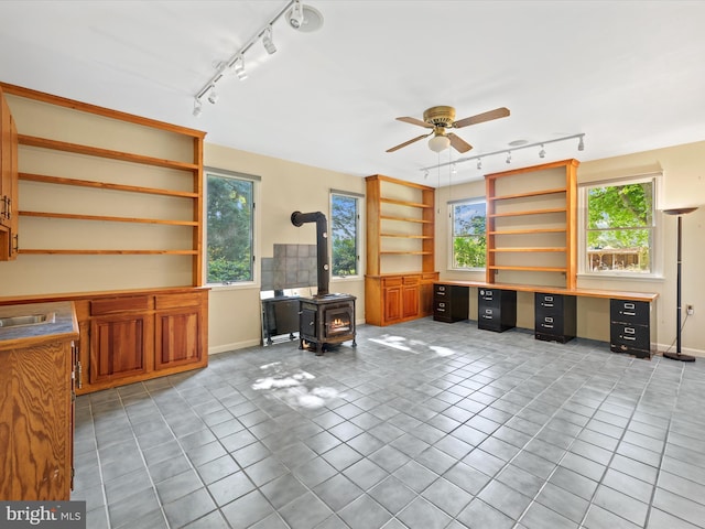 office featuring a wood stove, ceiling fan, rail lighting, and light tile patterned floors