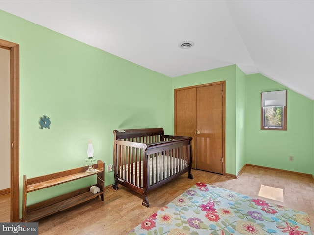 bedroom featuring a nursery area, vaulted ceiling, a closet, and light hardwood / wood-style flooring