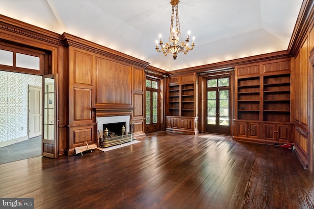 unfurnished living room with french doors, dark hardwood / wood-style flooring, built in shelves, vaulted ceiling, and a notable chandelier