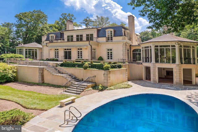 rear view of house featuring a sunroom and a balcony