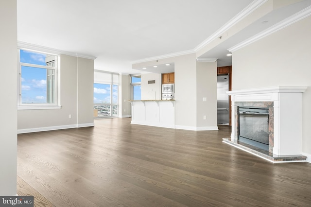 unfurnished living room featuring crown molding, baseboards, dark wood-style flooring, and a glass covered fireplace