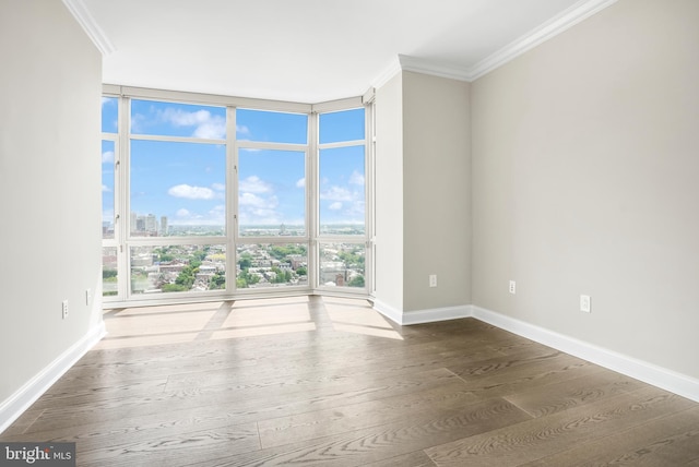 empty room with a view of city, floor to ceiling windows, crown molding, wood finished floors, and baseboards