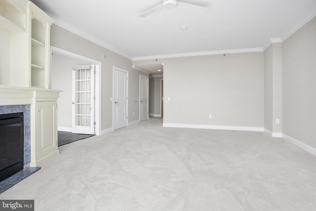 unfurnished living room with light carpet, ornamental molding, a premium fireplace, and baseboards