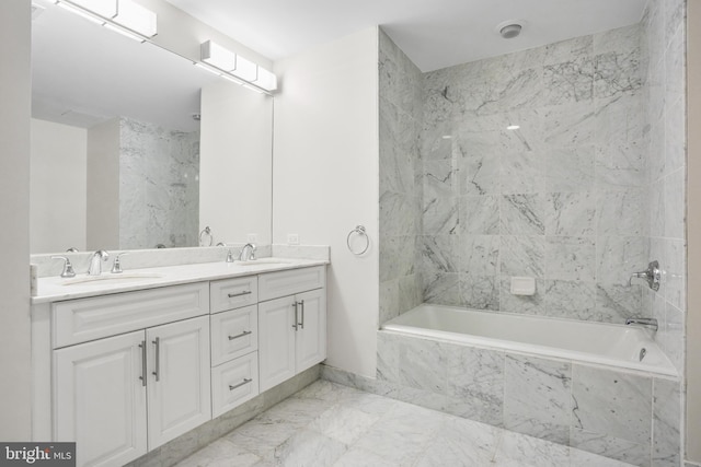 full bath with marble finish floor, a sink, tiled shower / bath combo, and double vanity