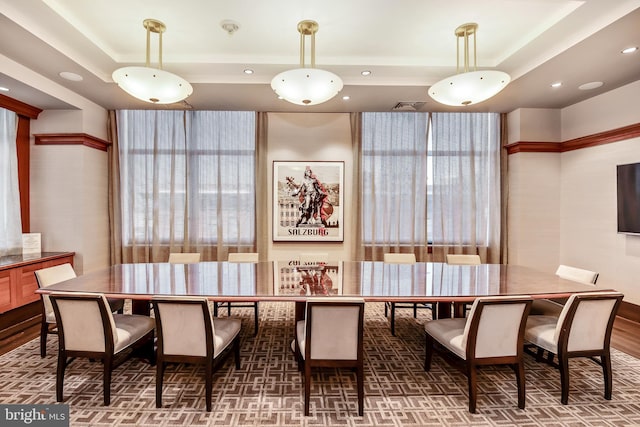 dining room with a raised ceiling, visible vents, and wood finished floors