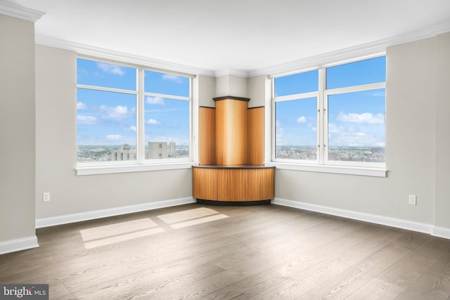 unfurnished room with a healthy amount of sunlight, ornamental molding, and dark wood finished floors