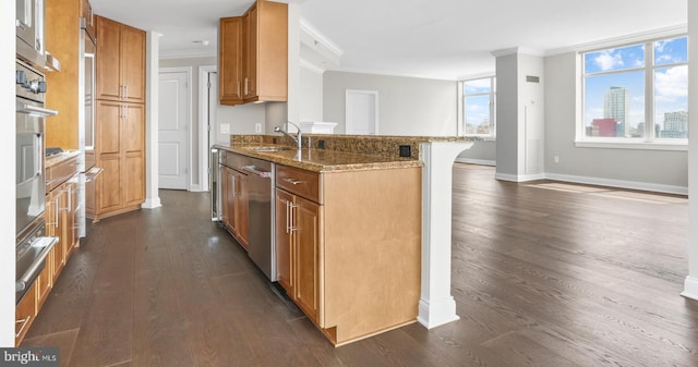 kitchen featuring brown cabinets, dark wood finished floors, crown molding, appliances with stainless steel finishes, and stone countertops