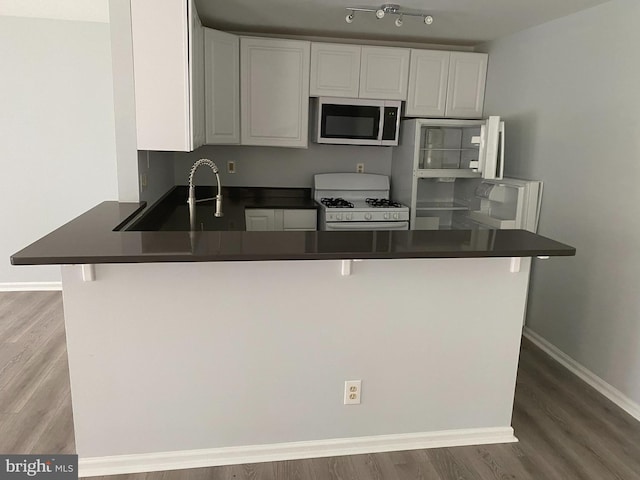 kitchen featuring kitchen peninsula, white cabinets, and white appliances