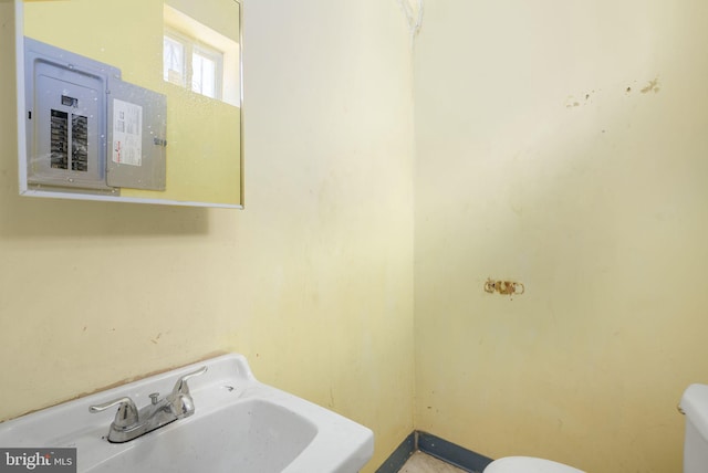 bathroom with electric panel, toilet, and sink