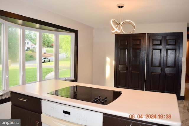 kitchen featuring black electric stovetop, oven, decorative light fixtures, and an inviting chandelier