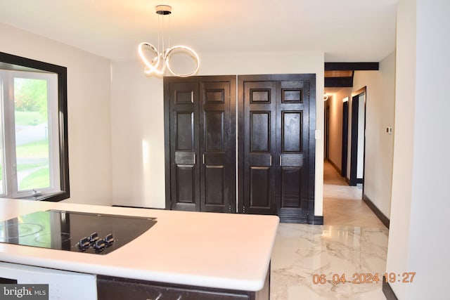 kitchen with black electric stovetop, hanging light fixtures, and an inviting chandelier