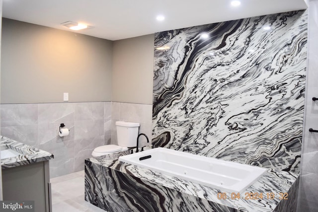 bathroom featuring a tub to relax in, vanity, tile walls, and toilet