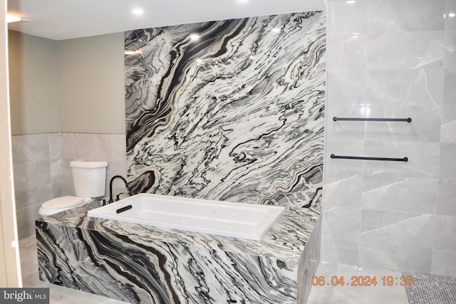 bathroom featuring toilet, tile walls, and tiled bath