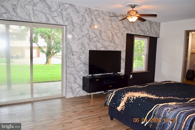 bedroom featuring access to exterior, hardwood / wood-style floors, ceiling fan, and tile walls