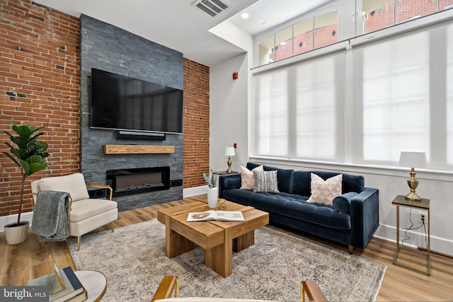 living room with a fireplace, wood-type flooring, and brick wall