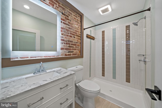 bathroom featuring tiled shower, vanity, hardwood / wood-style flooring, and toilet