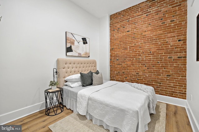 bedroom with light hardwood / wood-style flooring and brick wall