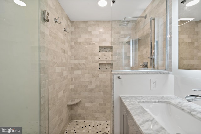 bathroom featuring a shower with door and vanity