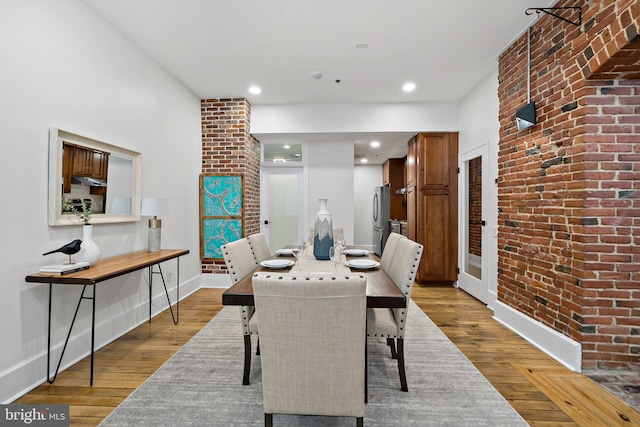 dining space with light hardwood / wood-style floors and brick wall