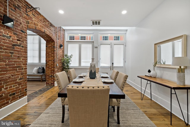 dining space featuring brick wall, french doors, and light hardwood / wood-style floors