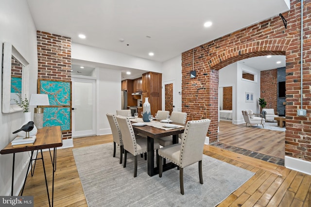 dining space featuring light hardwood / wood-style floors and brick wall