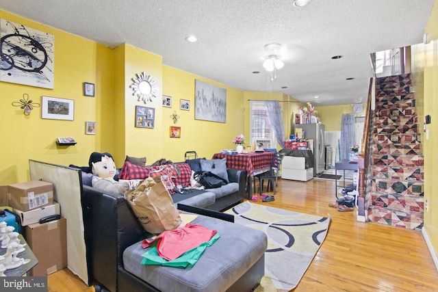 living room featuring hardwood / wood-style floors, ceiling fan, and a textured ceiling