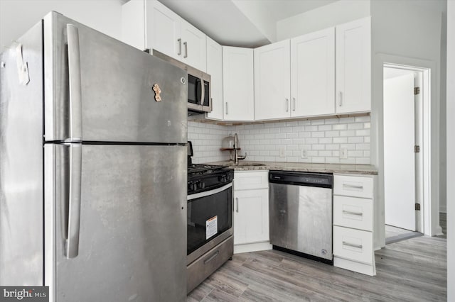 kitchen featuring stainless steel appliances, tasteful backsplash, sink, and light wood-type flooring