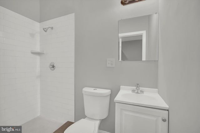 bathroom featuring a tile shower, vanity, and toilet